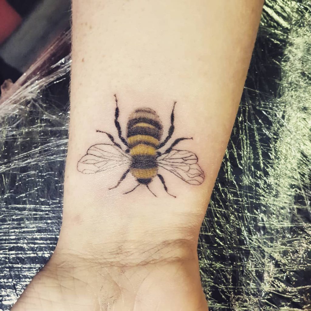 colour bee tattooed on wrist