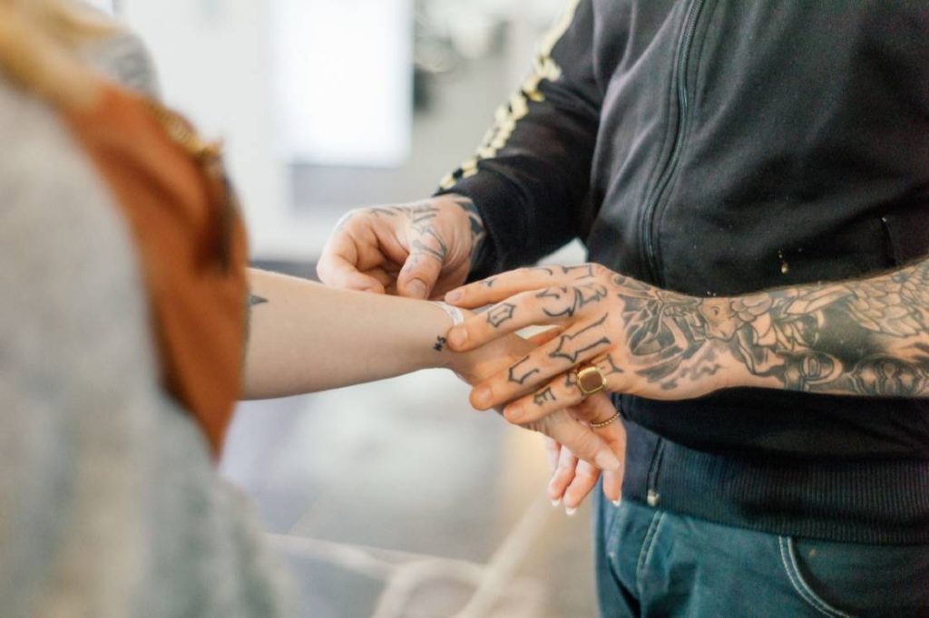 tattoo artist applying a stencil to client's arm