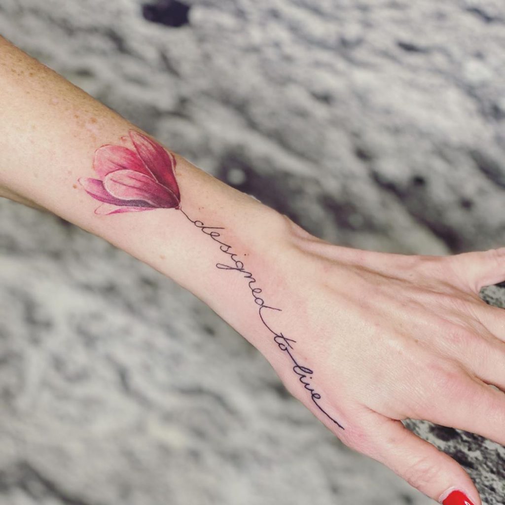 magnolia flower and writing tattoo on a woman's wrist