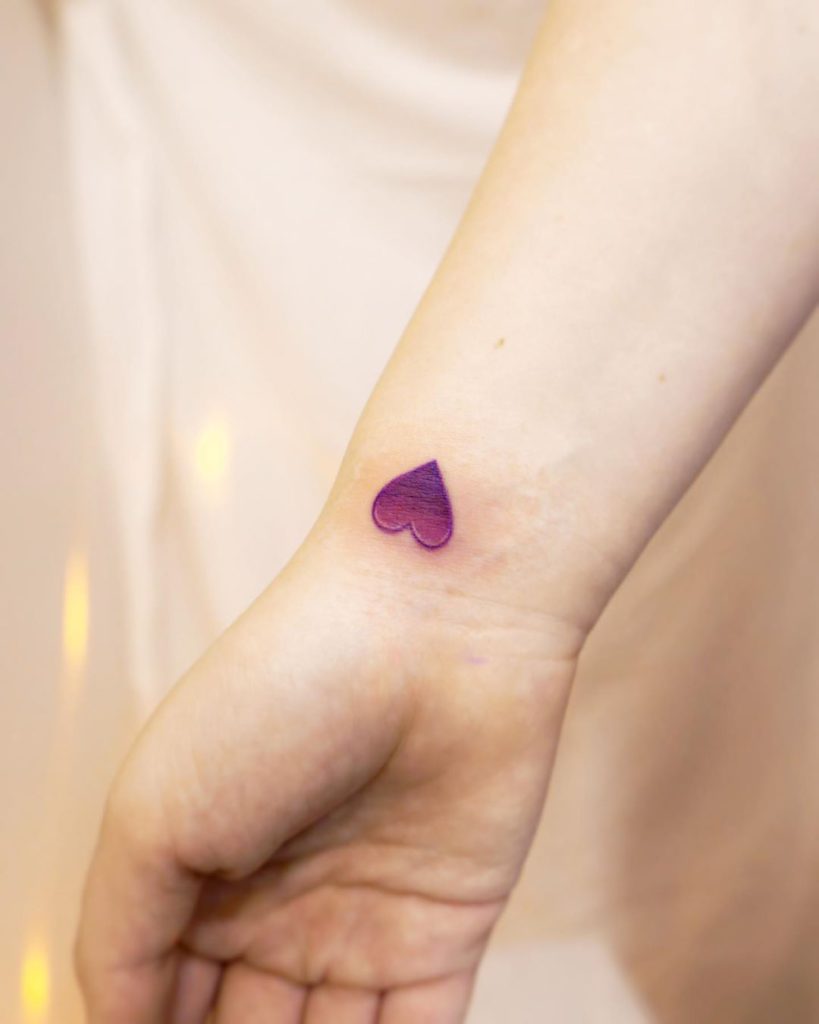 Tiny minimalistic heart tattoo placed on the shoulder